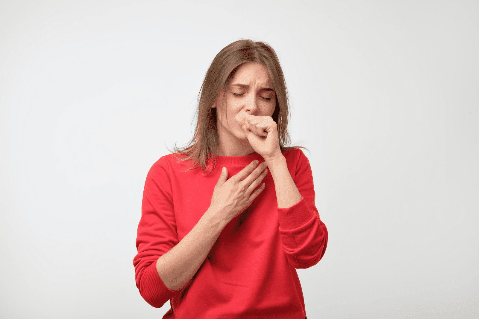 Woman coughing with hand on chest.