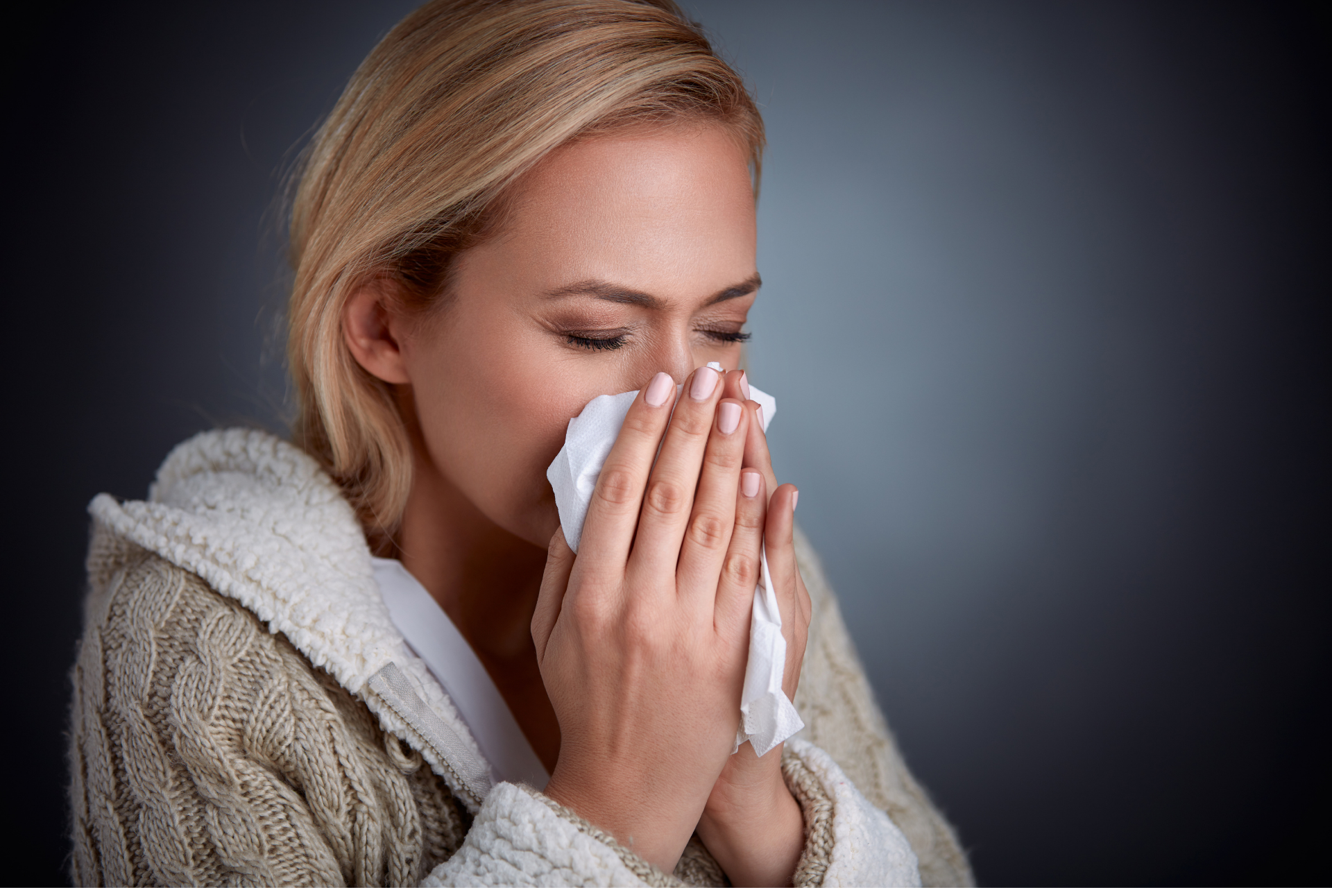 Woman holding a tissue to her nose, appearing sick or congested indoors