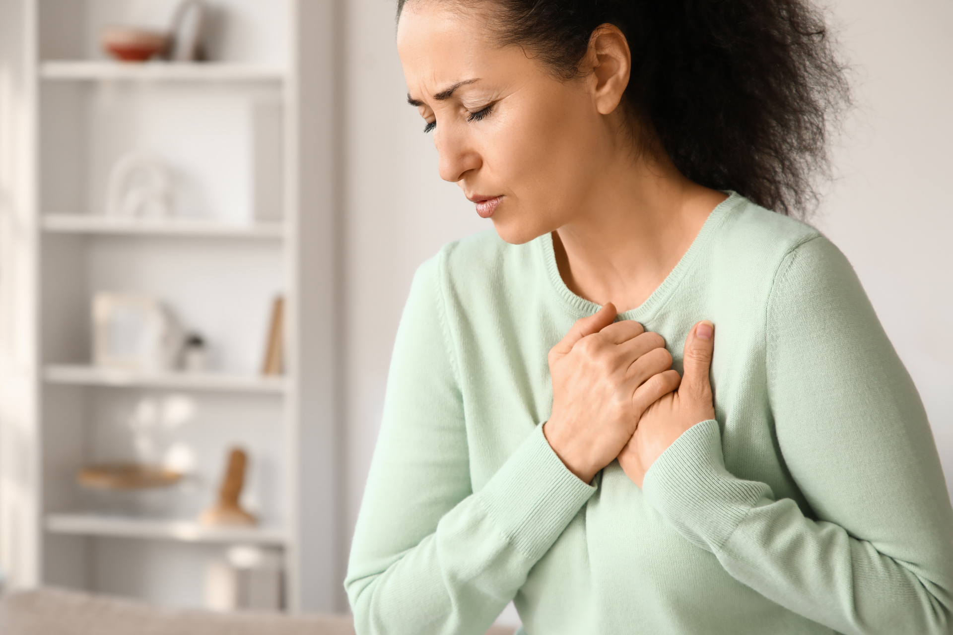 Woman holding her chest and appearing short of breath indoors