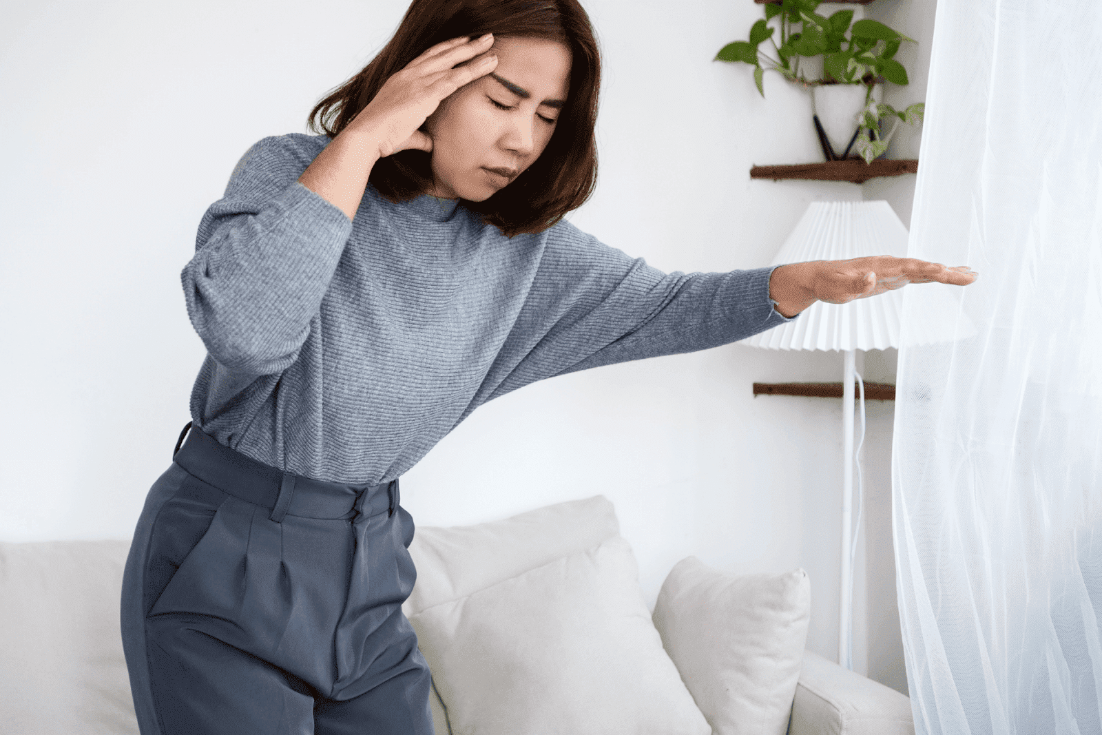 Woman holding her head and reaching out for balance, appearing dizzy.