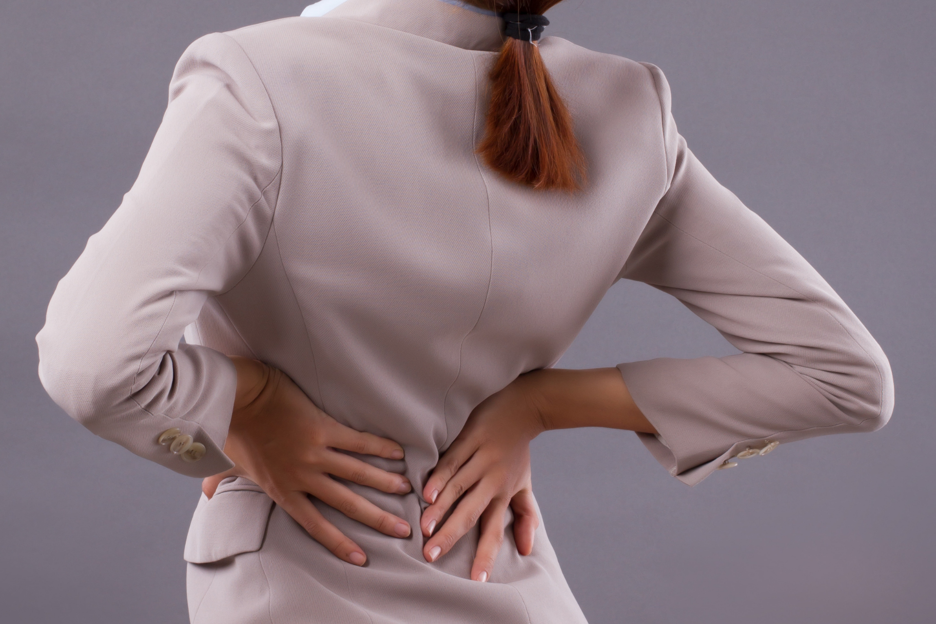 Woman holding her lower back in pain while standing