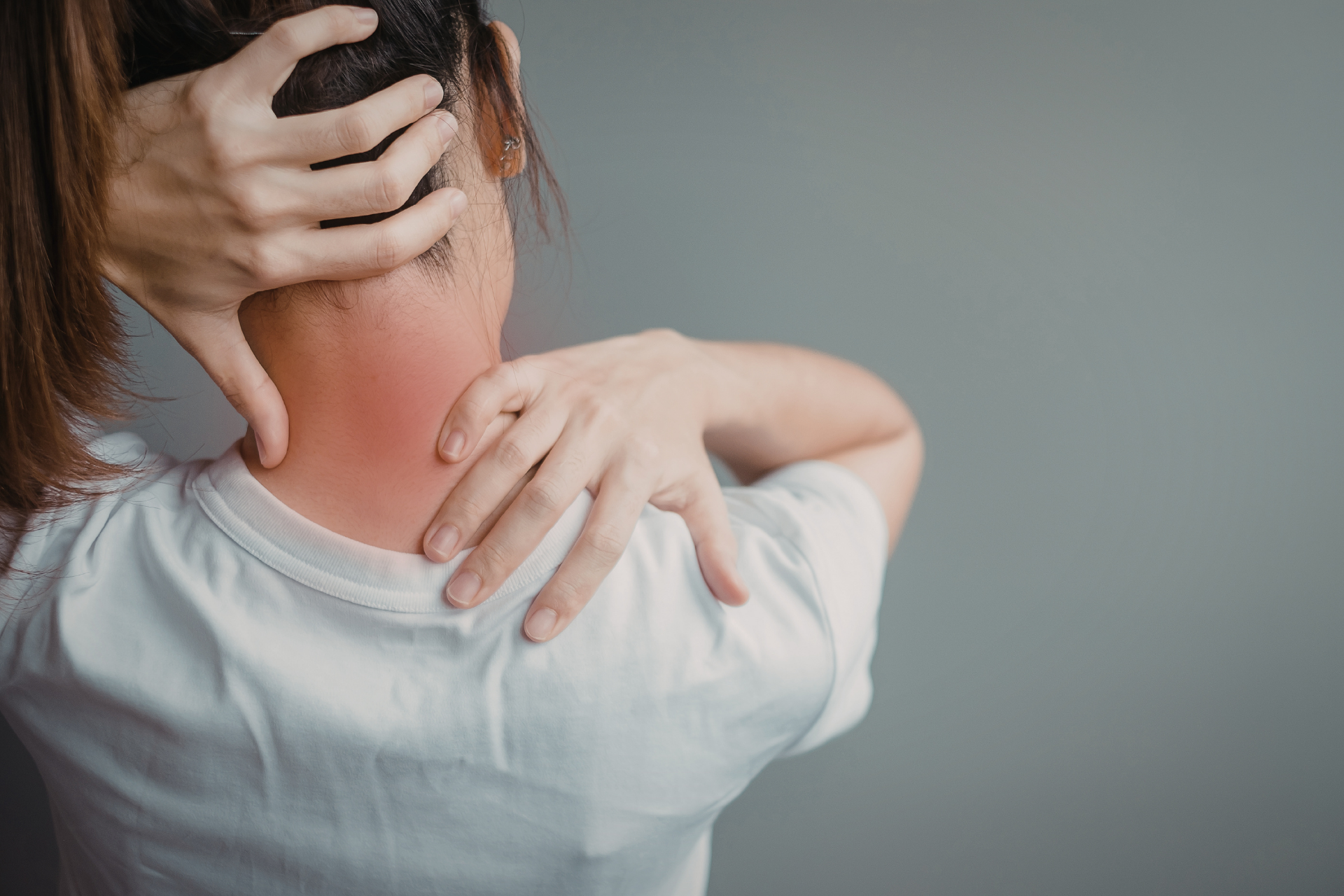 Woman holding her neck and upper shoulder with visible neck pain