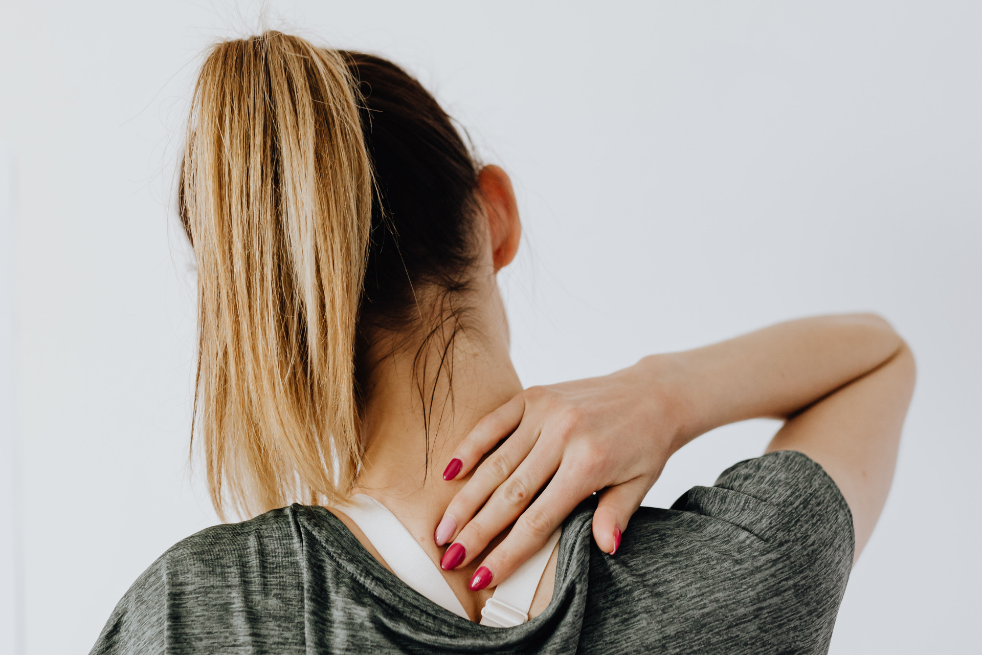 Woman holding the back of her neck, showing neck pain or stiffness