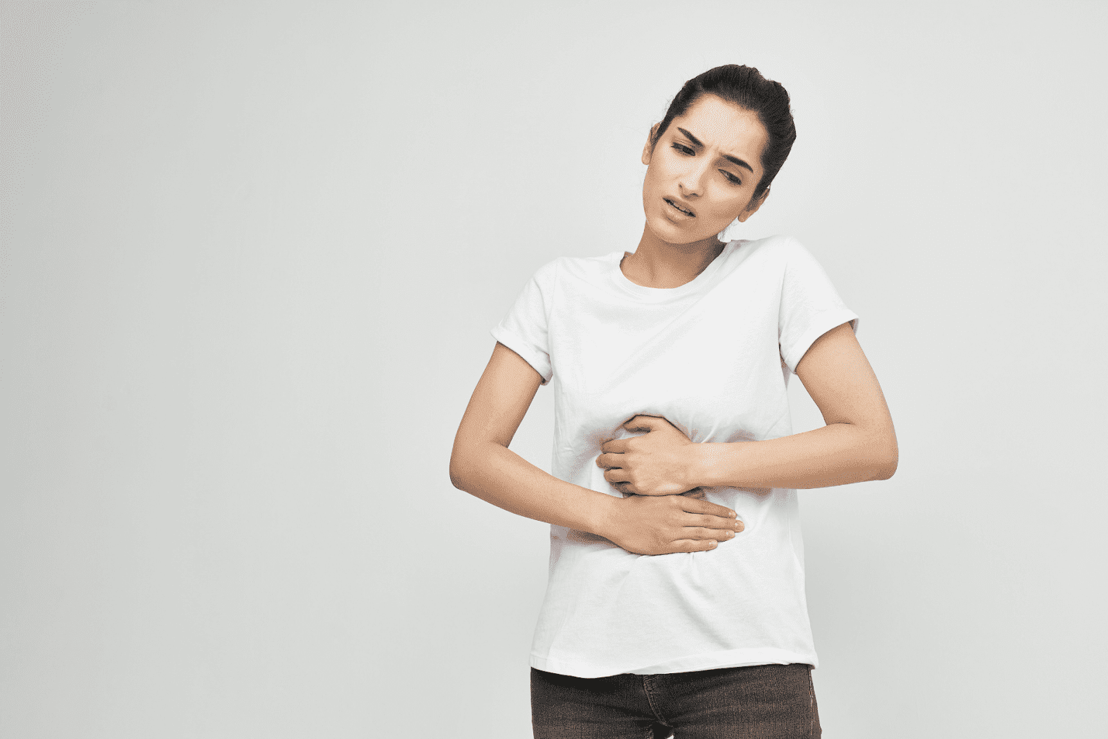 Woman in discomfort, clutching her abdomen with a pained expression