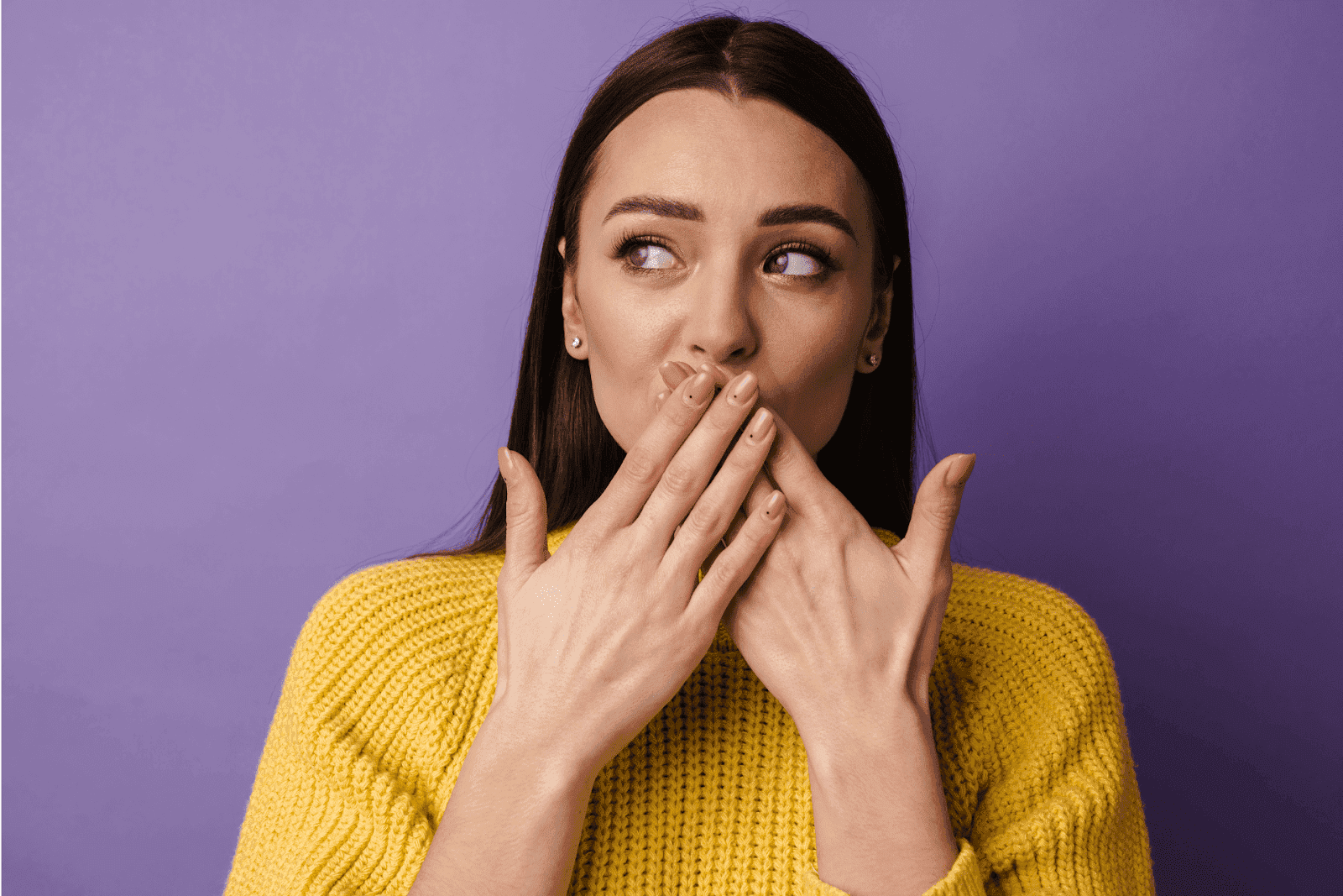 Woman in yellow sweater covering her mouth with both hands