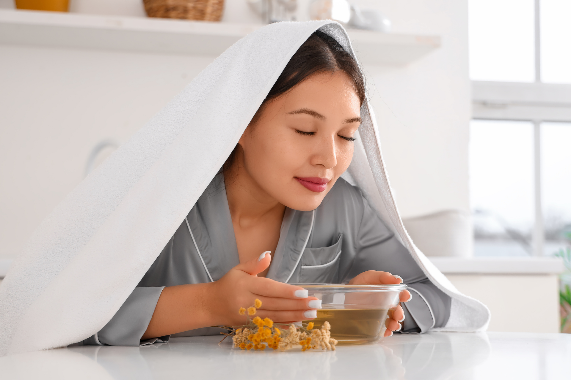 Woman inhaling steam from a bowl while covered with a towel