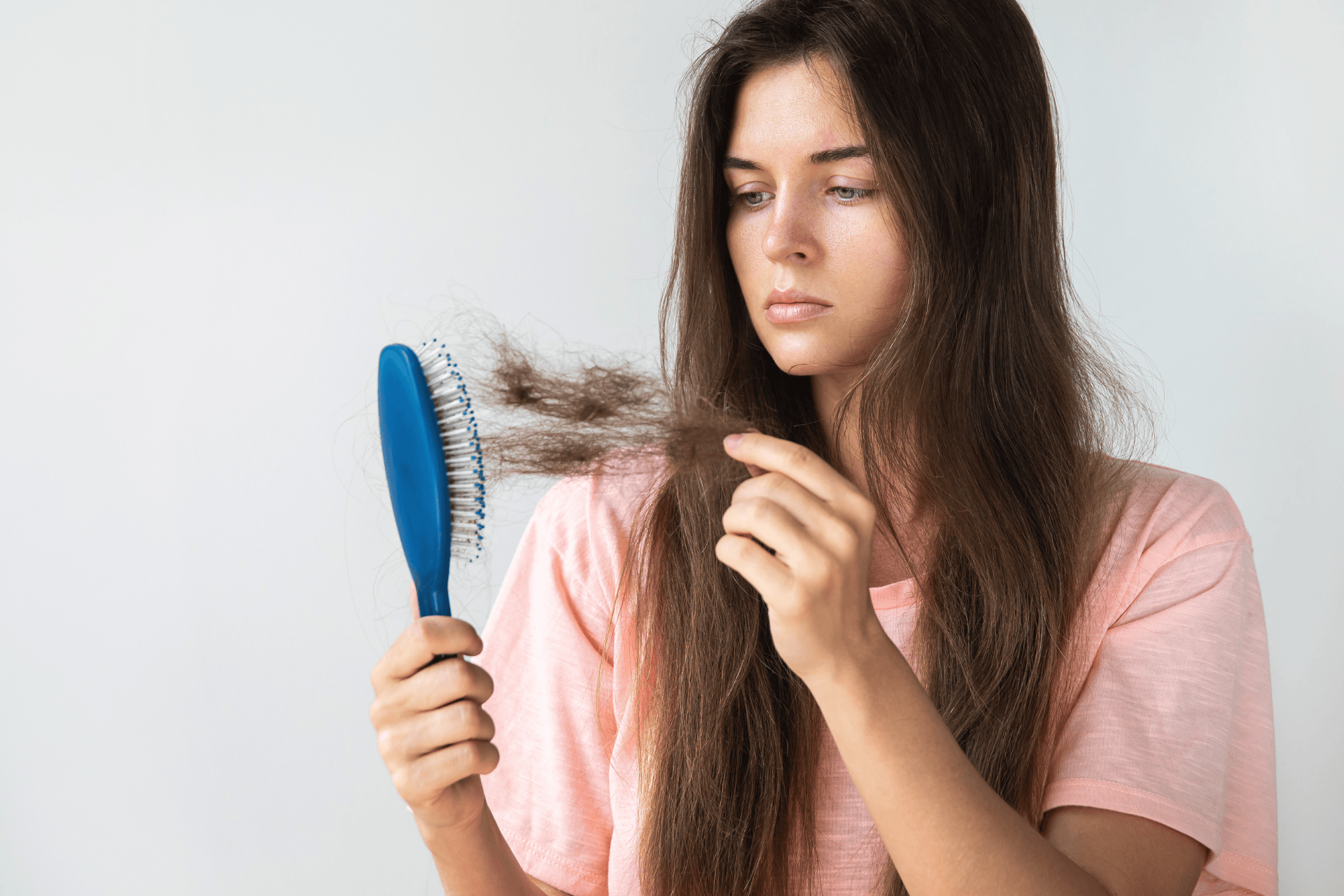 Woman looking at hair loss on a hairbrush with a concerned expression