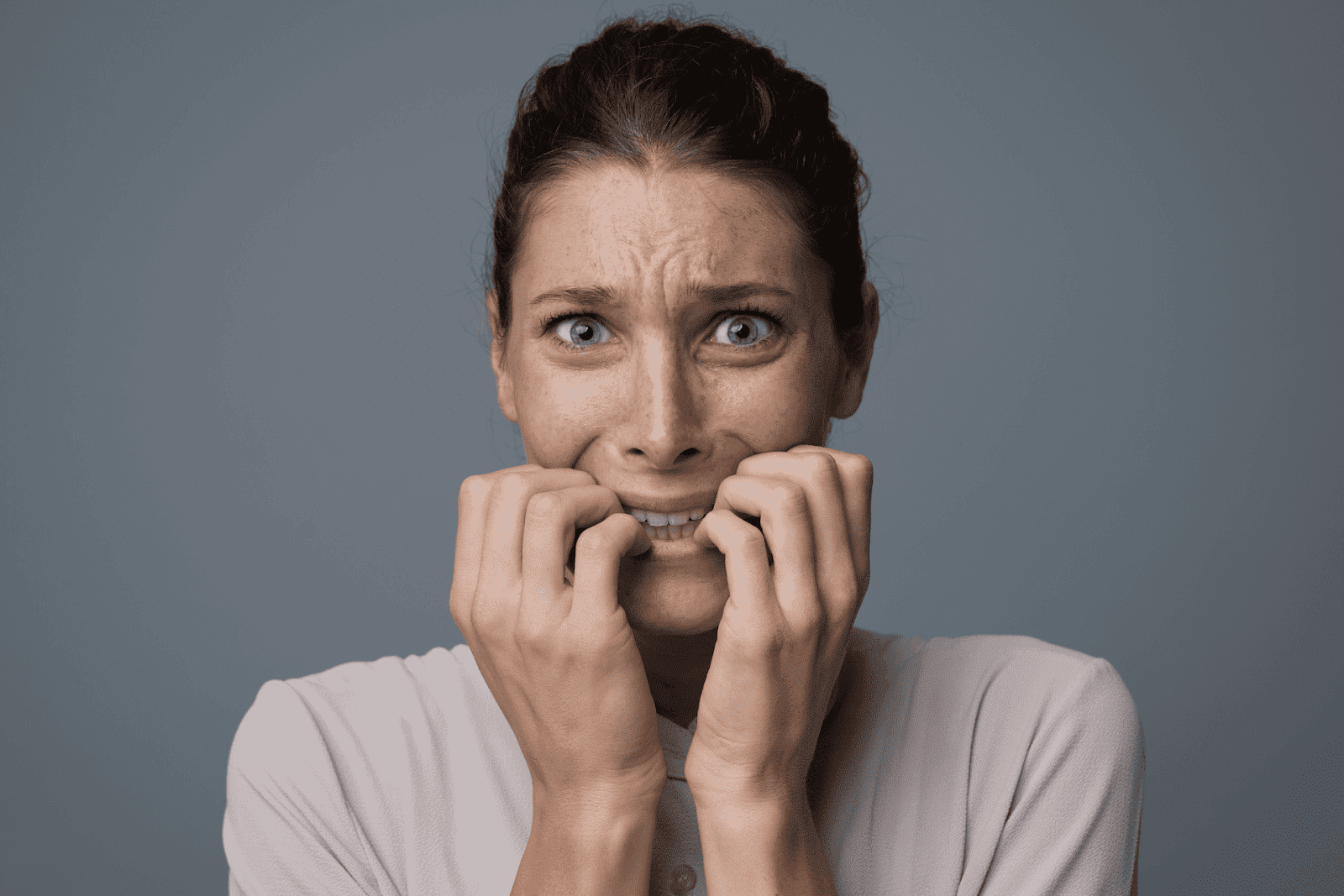 Woman looking distressed, biting her nails in fear or panic.