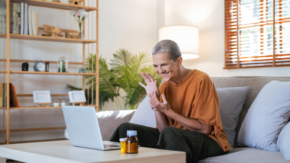 Woman waving into laptop on telehealth video call