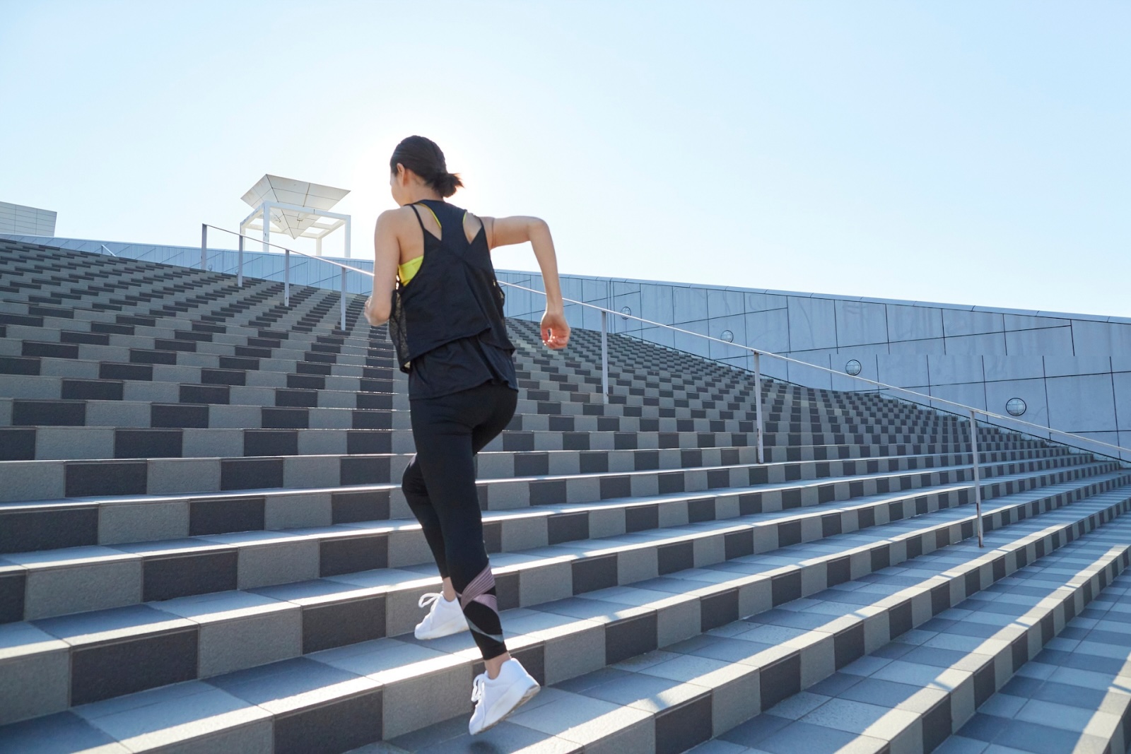 Woman running up outdoor stairs in athletic wear.