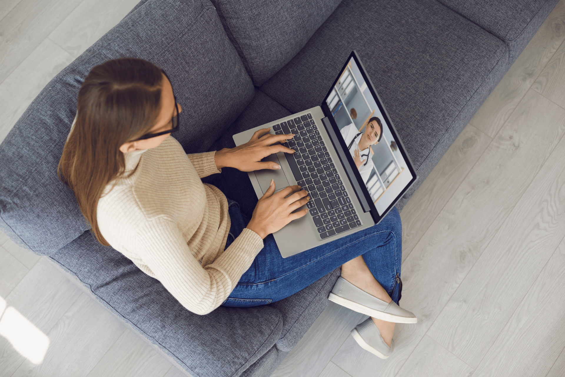 Woman sitting on a couch having an online video consultation with a doctor on her laptop.