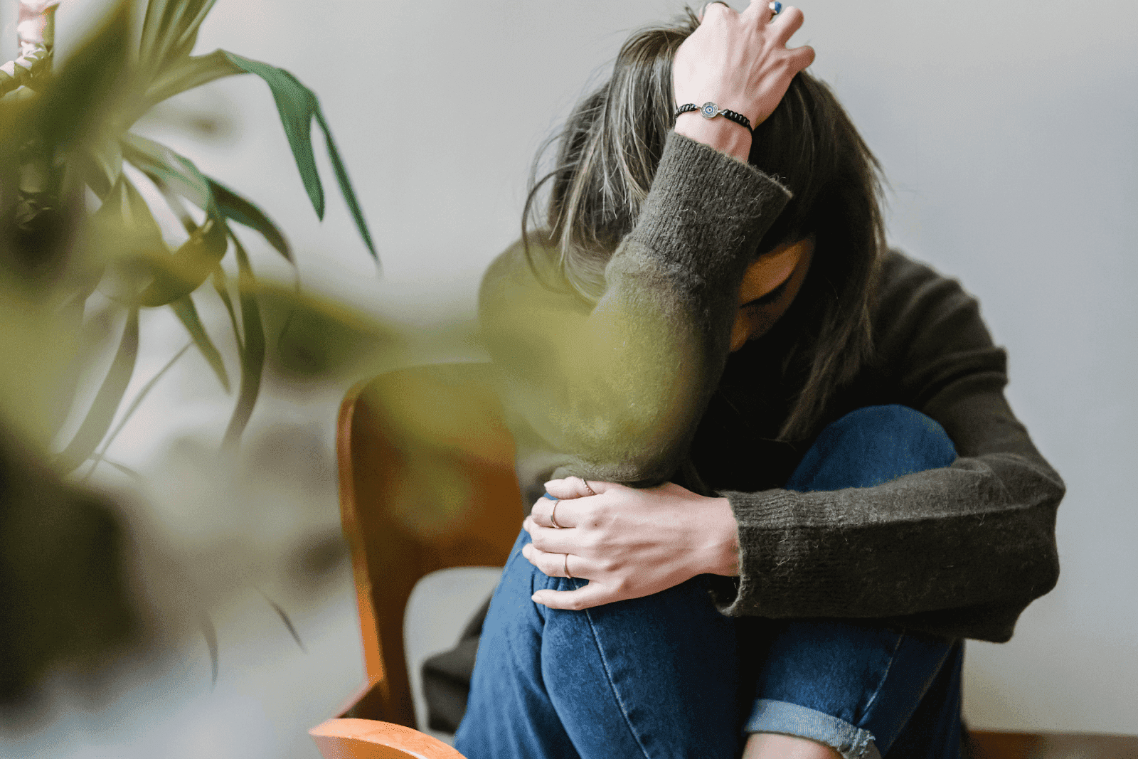 Woman sitting with head down and hand in hair, appearing distressed.