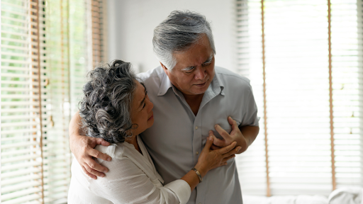 Woman supporting man who has his hand on his heart in pain