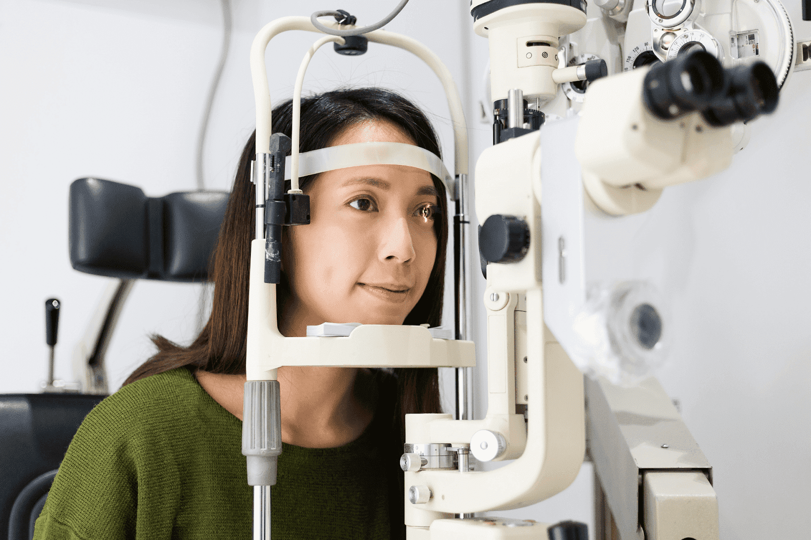 Woman undergoing an eye examination with a slit lamp at an optometrist’s office.