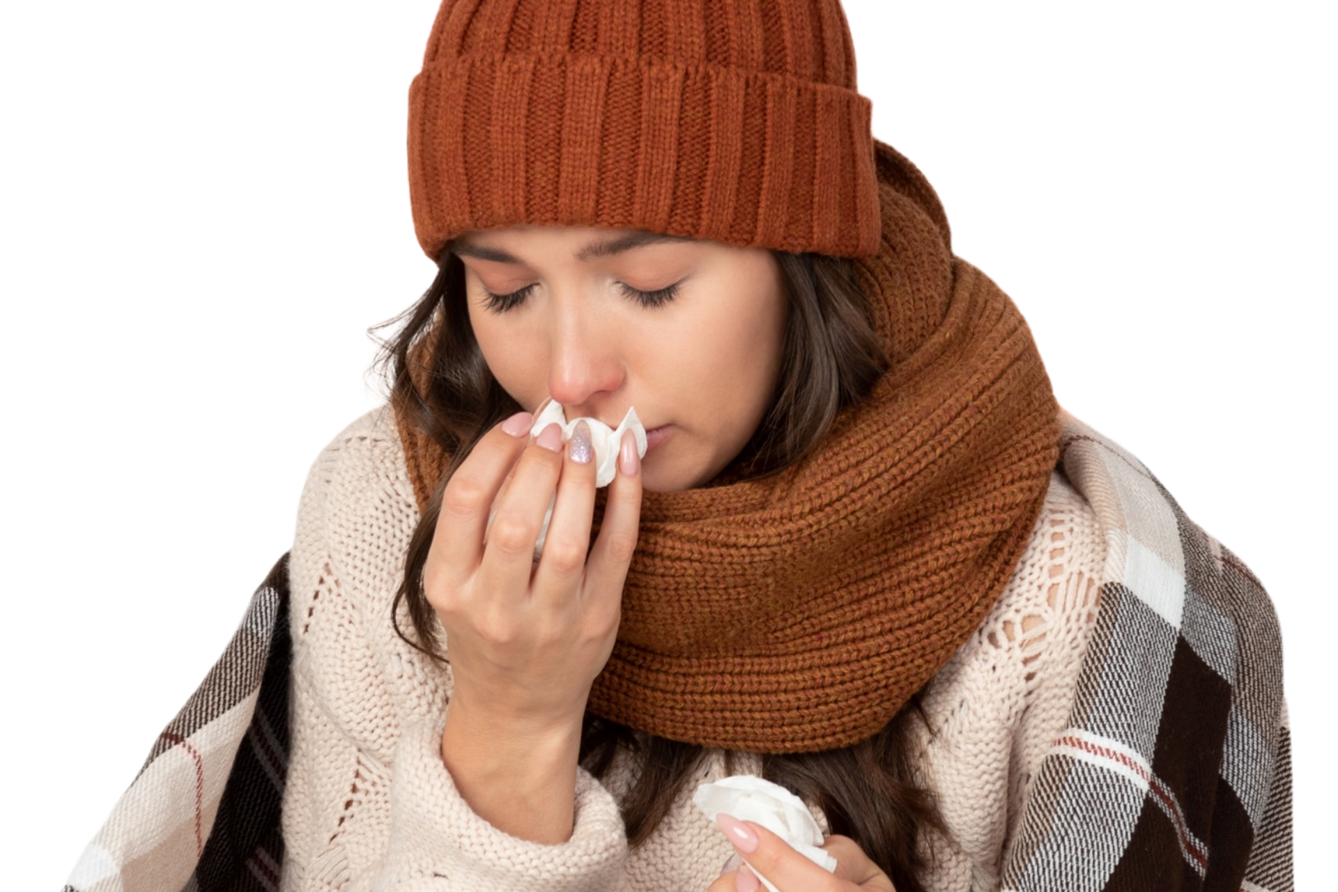Woman wearing a knit hat and scarf, blowing her nose with a tissue