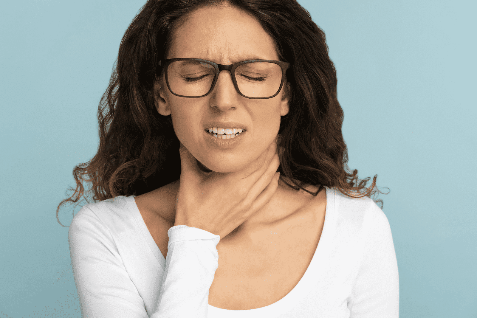 Woman with glasses holding throat in pain.