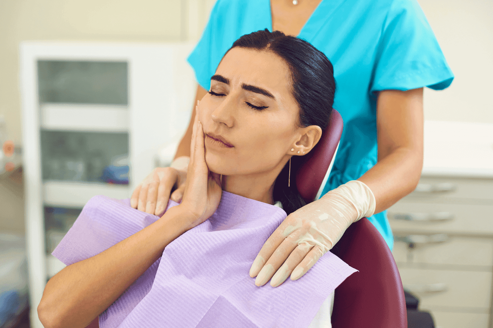 Woman with tooth pain sitting in dental chair.