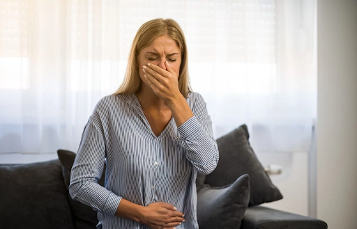 woman holding her stomach in pain and feeling nauseous due to food poisoning