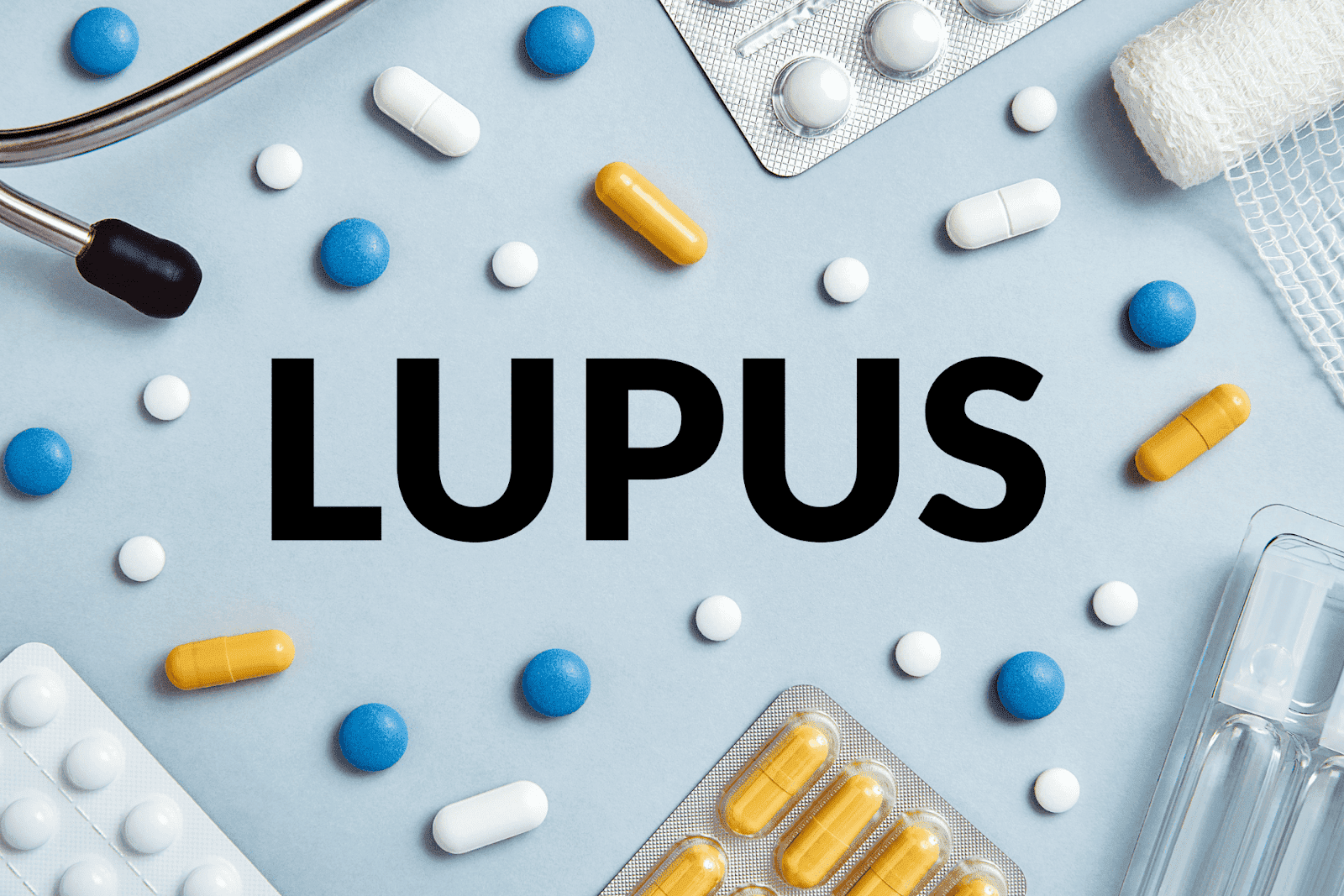 Word "LUPUS" surrounded by various pills and medical items on a blue background.