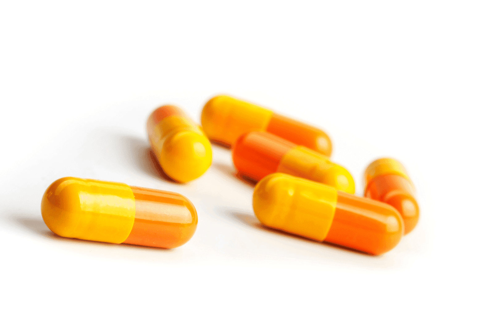 Yellow and orange capsules scattered on a white surface