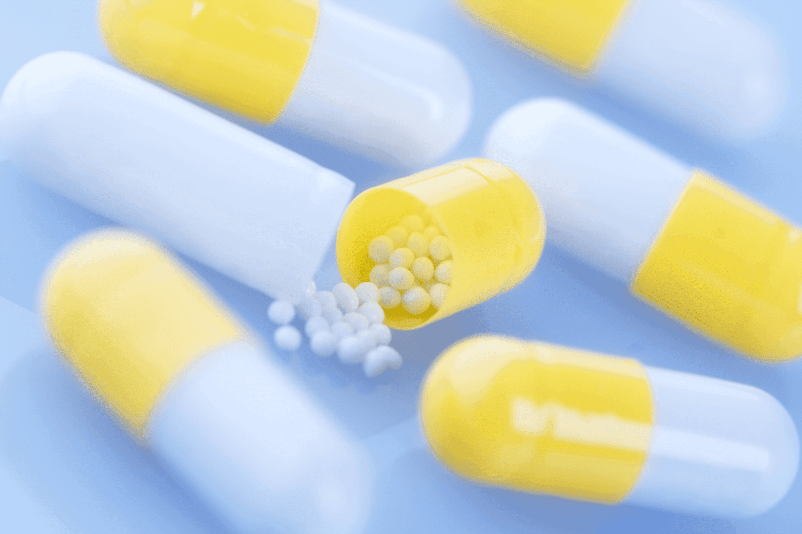 Yellow-and-white capsules, with one opened to show small white beads inside