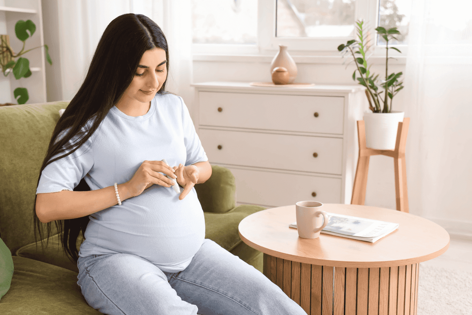 Young Pregnant Woman Using a Lancet Pen on a Sofa at Home